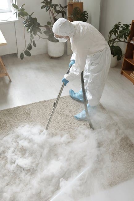 A woman operating a yellow vacuum cleaner on a patterned area rug in a living room with wooden flooring and a red leather sofa. The room is well-lit, and the carpet appears clean and dust-free, demons