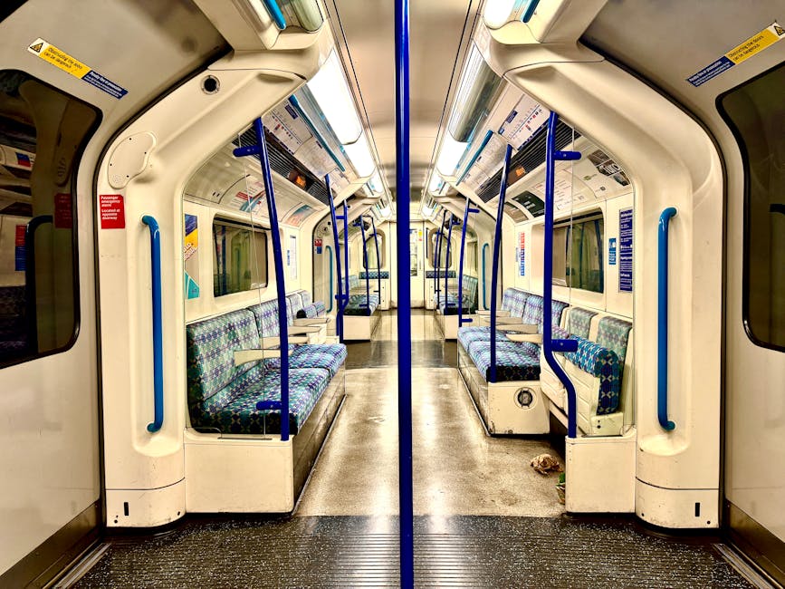 Finsbury Park station platform with a white overhead canopy, supported by metal columns painted with blue and white stripes, and multiple seating benches arranged along the platform. The ground is cle